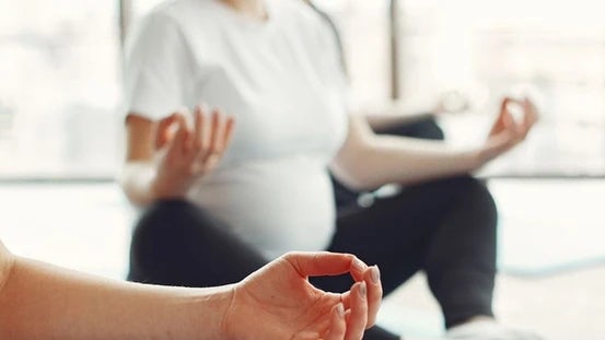 Raskaana olevat naiset keskittyvät rauhallisesti hengitysharjoituksiin joogamatolla äitiysfysioterapian rentoutumisharjoituksen aikana.